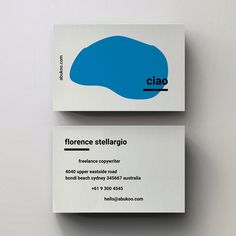 two business cards sitting on top of each other in front of a white background with blue letters