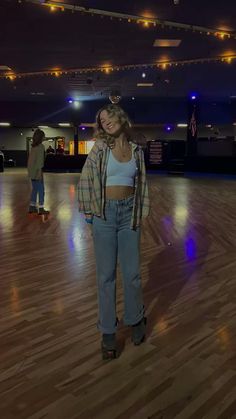 a woman standing on top of a hard wood floor next to a skateboarder