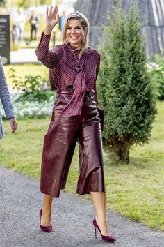 a woman in leather pants waves to the crowd