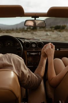 a man and woman sitting in the driver's seat of a car looking at each other