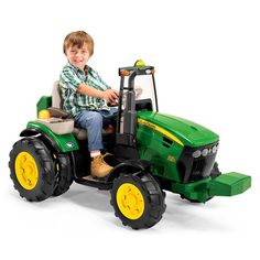 a young boy riding on the back of a green tractor