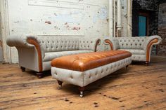 two couches sitting next to each other on top of a wooden floor in an old building