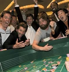 a group of men standing next to each other in front of a roule table