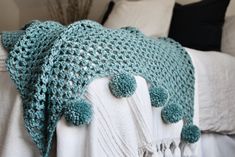 a crocheted blanket with pom - poms on it is sitting on a bed