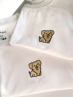 two t - shirts with embroidered dogs on them, one is white and the other is brown