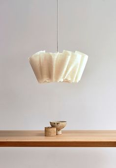 a wooden table topped with two bowls and a light hanging from it's ceiling