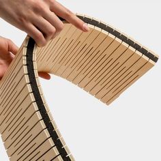 a person is holding a piece of wood that looks like a train track, and it's being held by another hand