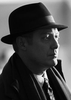 black and white photograph of a man wearing a fedora, scarf, and tie