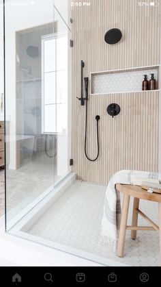 a walk in shower sitting next to a wooden bench