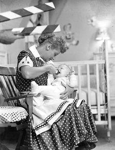 an old black and white photo of a woman holding a baby in a rocking chair