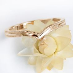 two gold wedding bands on top of a flower