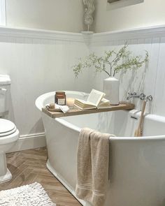 a white bath tub sitting in a bathroom next to a toilet and a sink with a book on top of it