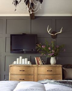 a bedroom with a bed, dresser and television on the wall above it is decorated with flowers