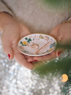 a woman holding a plate with some jewelry on it