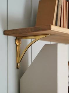 a wooden shelf with books on it and a book case in the corner behind it