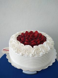 a cake with white frosting and strawberries in the middle on a blue table