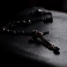 a rosary on a black leather surface with a cross hanging from it's end