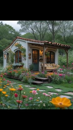 a small white house surrounded by flowers and trees