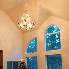 a living room filled with furniture and a christmas tree in front of two large windows