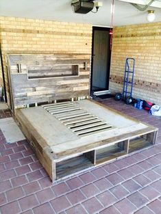 a bed made out of pallet wood sitting on top of a red brick floor