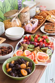 a wooden table topped with lots of plates and bowls filled with different types of food