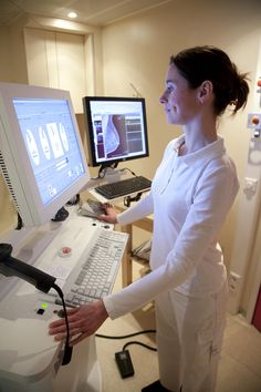 a woman standing in front of a computer monitor with a keyboard and mouse on it