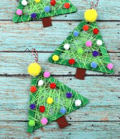 three christmas trees made out of yarn and pom - poms on a wooden table