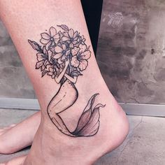 a woman's foot with flowers in a vase tattoo