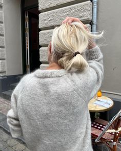 a woman with blonde hair wearing a gray sweater