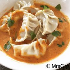 a white bowl filled with dumplings covered in sauce