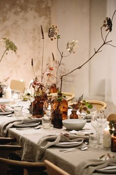 the table is set with plates, glasses and vases filled with flowers on it