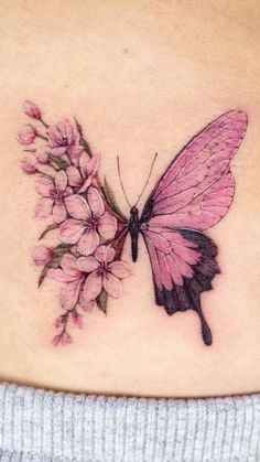 a woman's stomach with a butterfly and flowers tattoo on the back of her belly