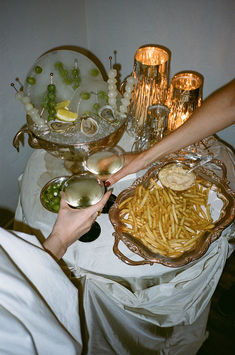 a table topped with plates and bowls filled with different types of food next to candles