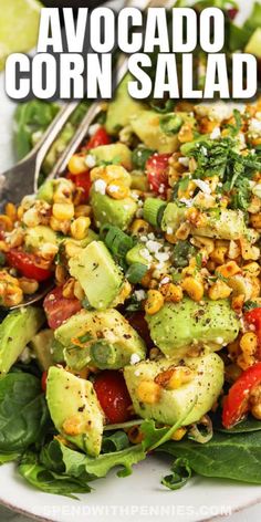 avocado corn salad on a white plate with a fork and green lettuce