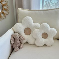 a stuffed animal sitting on top of a white couch next to pillows and a mirror