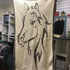 a blanket with a horse drawn on it is hanging in a room next to a couch