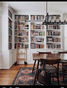 a dining room table with bookshelves full of books on the wall behind it