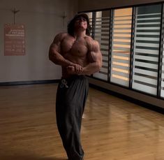 a shirtless man is standing in an empty room with his hands on his hips