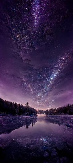 the night sky is filled with stars and clouds above a body of water that's covered in ice