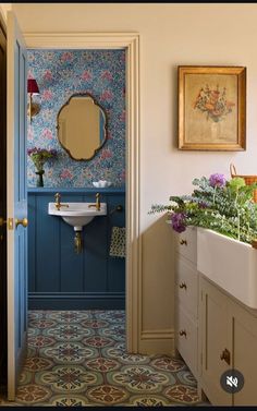 a blue and white bathroom with flowers on the floor, sink and mirror in it