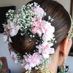 a woman with flowers in her hair and jewelry on her neck, looking down at the ground