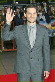 a man in a suit waves to the crowd