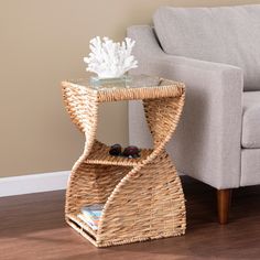 a wicker end table with a glass top on the floor next to a couch