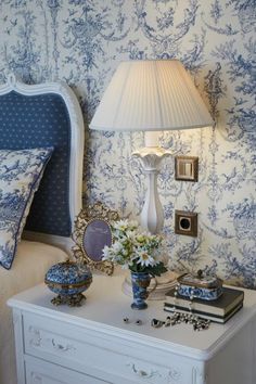 a bedroom with blue and white wallpaper, a bed headboard and lamp on the nightstand