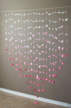 a pink and white mobile hanging from the ceiling in front of a wall with flowers on it