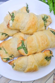 three croissants with spinach and cheese on a white plate next to parsley