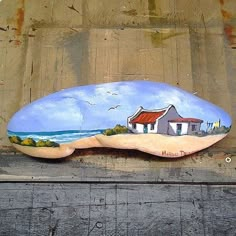 a painted rock sitting on the side of a building next to a wooden fence with a house in it