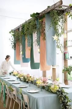 a long table is decorated with hanging plants and candles