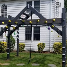 a wooden structure with balls on it in front of a house