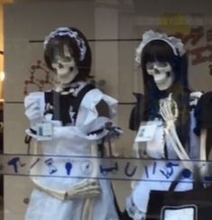 two mannequins dressed as skeletons in front of a store window with writing on them